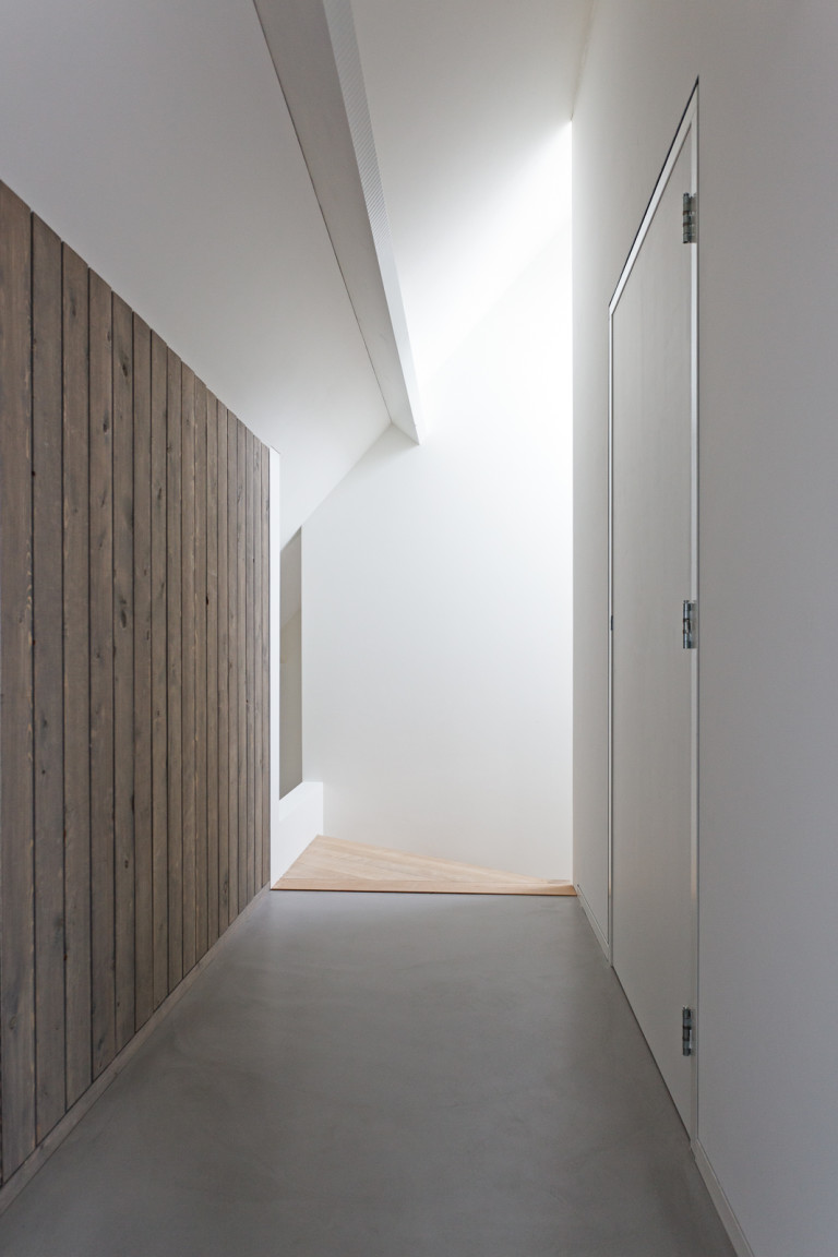 Overloop met stucwerk, betonvloer en houten wanden